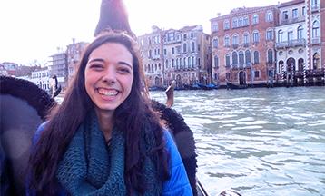 A portrait photo of Maggie Lyman sitting on a boat in a river.